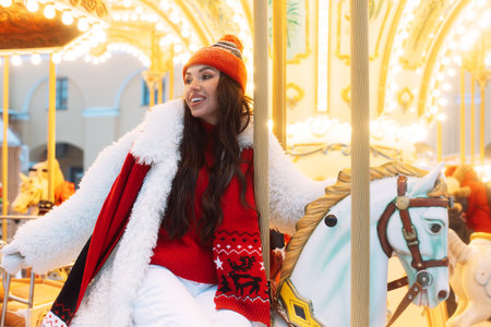 Beautiful woman on a carousel. The model is saddled on a horse and having fun during the winter holidays.の写真素材