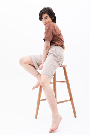 Fashion female model with short hair sitting on the chair over white background.の写真素材