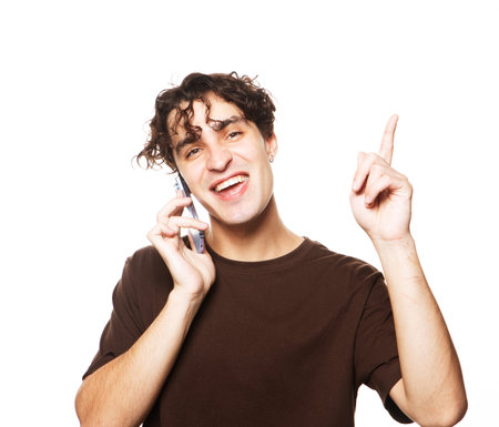 Great news. Happy young brunette man in shirt gesturing and smiling while talking on the mobile phone.の写真素材