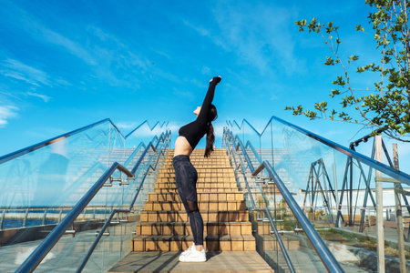 A young sporty woman doing exercises on the stairs outdoors early in the morning.の写真素材