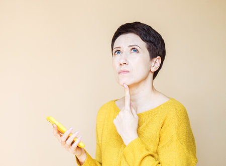 technology, communication and people concept: happy middle age woman with smartphone over beige background.の写真素材