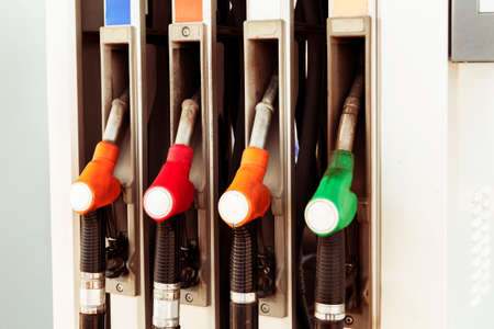 Horizontal shot of four fuel pumps, painted in different colors, at a gas station