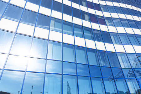 Reflection of the sun and city building silhouettes in the glass of an office building
