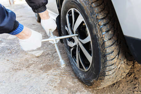 The master turns the wheel nuts of the car. Replacing wheels
