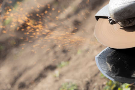Sharpening garden shovel by hand grinder. Sparks from sharpening a shovel by hand grinder. Outdoor....
