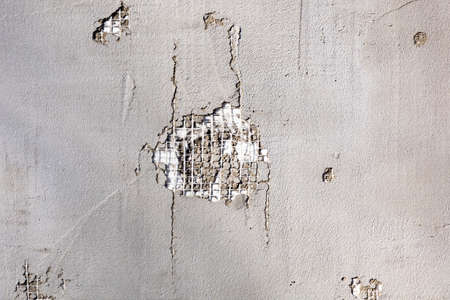 View of a peeling piece of wall. Damaged part of the wall. Damaged plaster surface. Wall with...