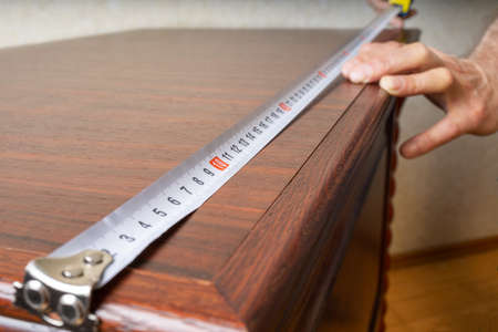 Image of the measuring process of the table with a measuring tape. Measuring roulette. Construction conceptの写真素材