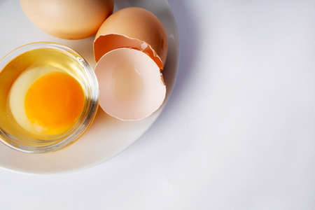 Image of yolk and squirrel in a transparent round cup on a plate. Egg in a transparent cup on a...