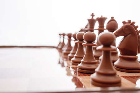 Image of chess pieces on a chessboard. World Chess Day. International Chess Day. July 20. Side view. Closeup. White background. Focus on the midle figuresの写真素材