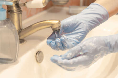 Washing hands in medical gloves under the faucet with water. Washing hands with soap and water. Hand hygiene conceptの写真素材