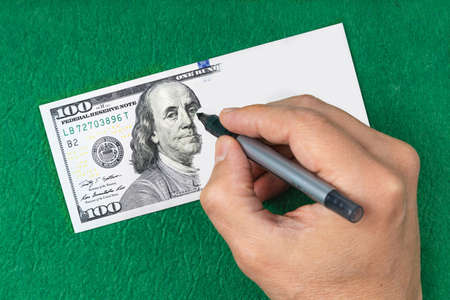 Making fake money. Hand draws a dollar. Counterfeiting money. Green Blur background. Conceptの写真素材