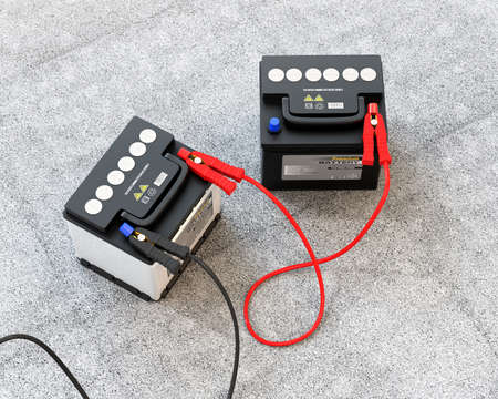 Generic maintenance-free car batteries connected by jumper cable on concrete ground. 3D rendering image.の写真素材