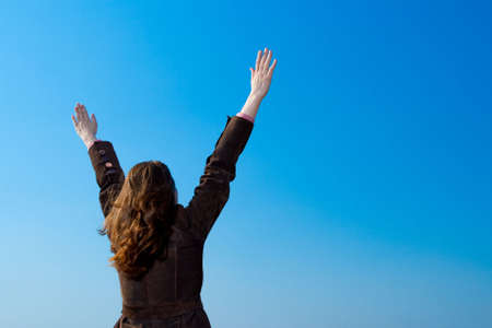 woman rising up hands over blue skyの写真素材