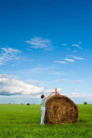 woman and boy in the field, boy sitting on hay stackの写真素材