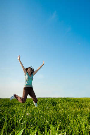young woman jumping on geen fieldの写真素材