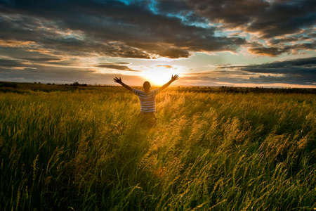 happy man in green filed before sunsetの写真素材