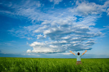 man in summer field under clouds on blue skiesの写真素材