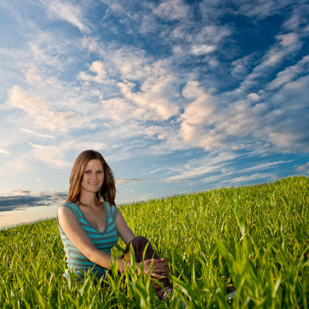smiling woman sitting on grassの写真素材