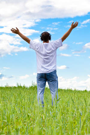 man in summer field wearing headphonesの写真素材
