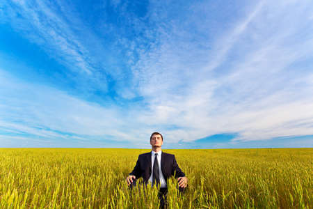 young businessman sitting on fieldの写真素材