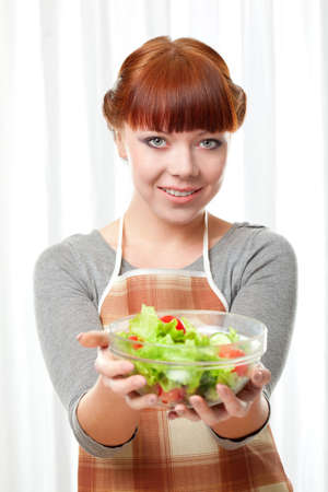 ginger housewife holding glass plate with salad over whiteの写真素材