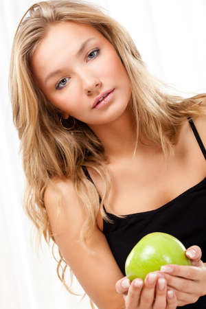 beautiful blonde woman sitting on bed and holding appleの写真素材
