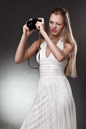 blonde woman with vintage camera over dark backgroundの写真素材