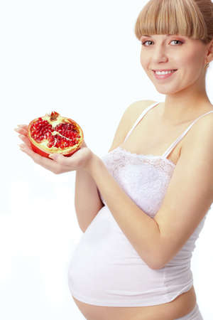 pregnant woman with red pomegranate over whiteの写真素材