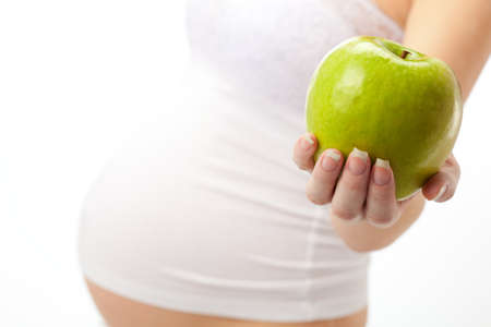 belly pregnant woman with green apple  over  whiteの写真素材