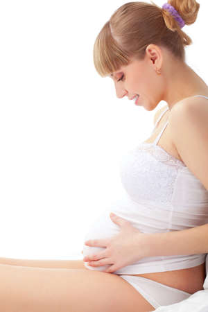 beautiful pregnant sittng woman on white bedの写真素材