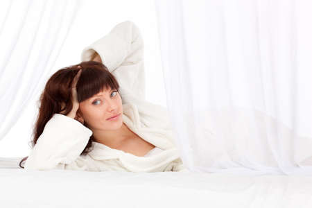 beautiful woman laying on bed behind the curtainの写真素材