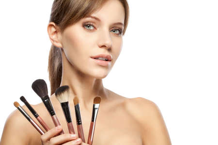 beautiful woman holding makeup brushes set over whiteの写真素材