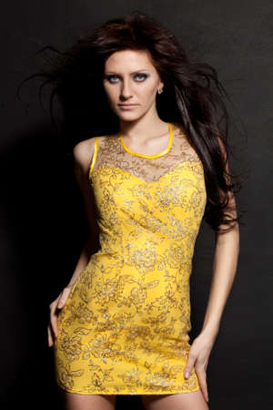beautiful woman posing wearing yellow dress over black wallの写真素材