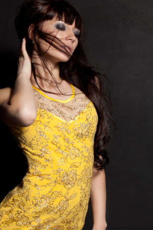 beautiful woman posing wearing yellow dress over black wallの写真素材