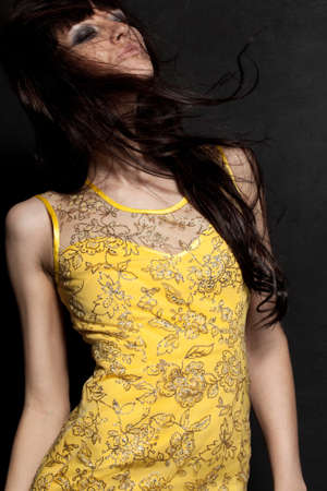 beautiful woman posing wearing yellow dress over black wallの写真素材
