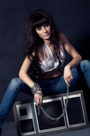 beautiful garage style weared woman sitting on speaker near black wallの写真素材
