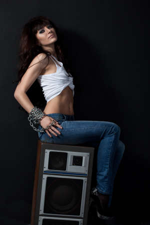beautiful garage style weared woman sitting on speaker near black wallの写真素材
