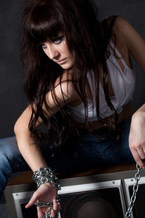 beautiful garage style weared woman sitting on speaker near black wallの写真素材
