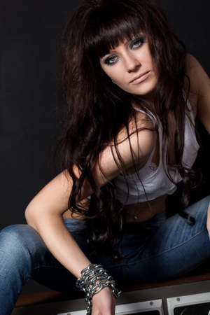 beautiful garage style weared woman sitting  near black wallの写真素材