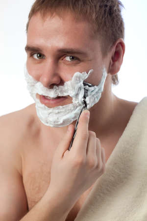 attractive man shaving his face over whiteの写真素材