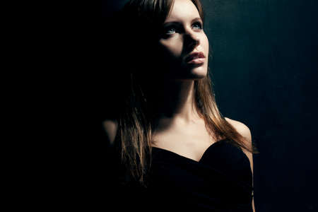 beautiful woman portrait wearing black dress over dark backgroundの写真素材