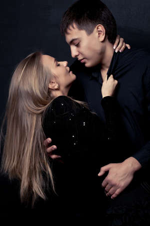 man and woman couple wearing back over dark wallの写真素材