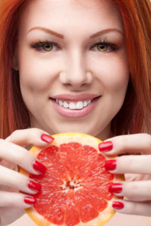 red-haired woman holding grapefruit over white backgroundの写真素材
