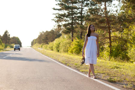 woman walking along the asphalt roadの写真素材