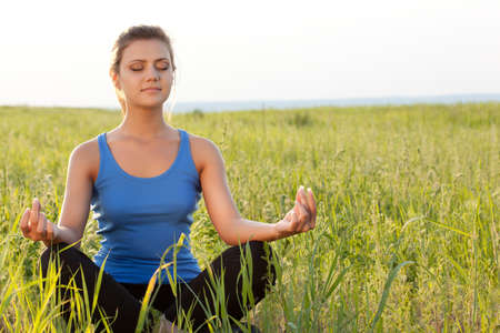 beautiful woman on filed in lotus poseの写真素材