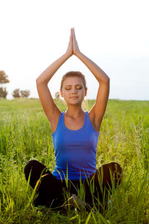 beautiful woman on filed in lotus poseの写真素材