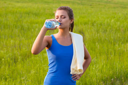 sport woman drinking water on fieldの写真素材
