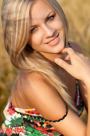 beautiful woman sitting on wheat fieldの写真素材