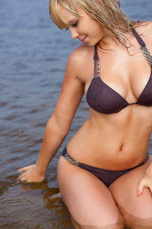 beautiful blonde woman in water wearing brown bikiniの写真素材