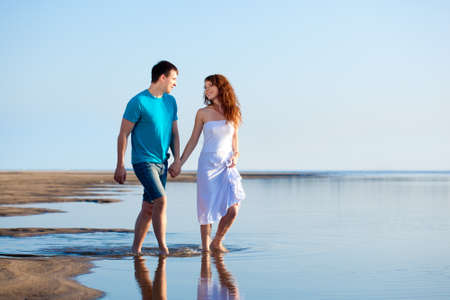 young adult happy couple walking on beachの写真素材